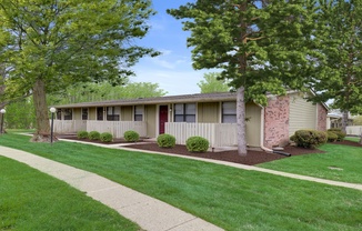 A row of houses with green lawns and trees in the background.