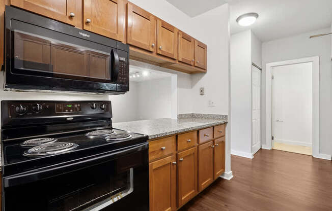 A black microwave oven is mounted above a black stove with a silver handle.