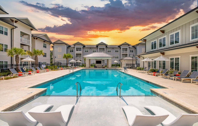 a swimming pool at sunset with chairs around it