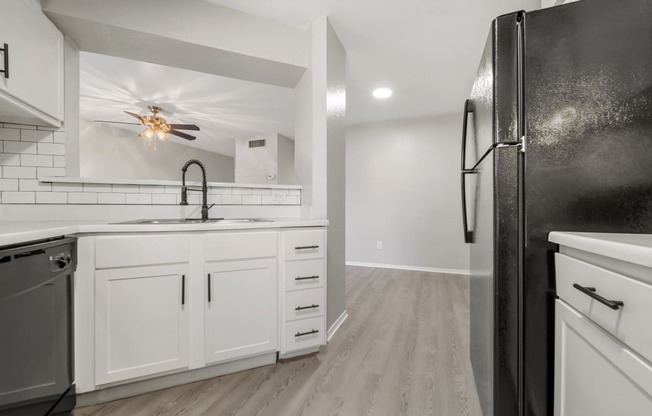 a kitchen with white cabinets and black appliances