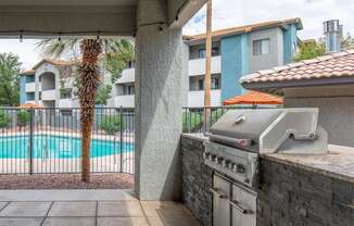 A grill is on a patio next to a pool.