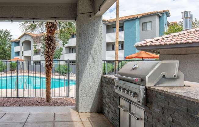 A grill is on a patio next to a pool.