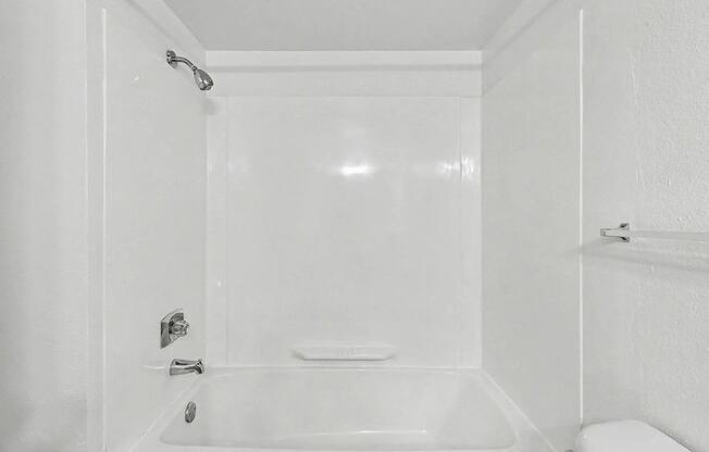 A white bathroom with a bathtub and toilet at Trappers Cove Apartments, Lansing