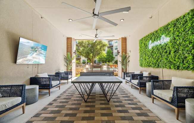 A patio with a table, chairs, and a green wall with the word