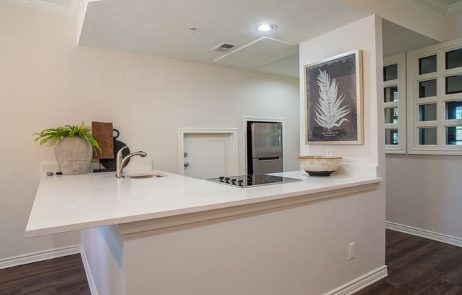 a kitchen with a white counter top and a sink and a refrigerator