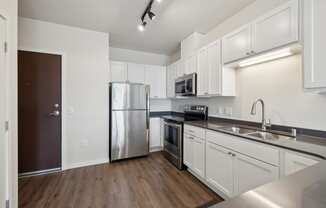 an empty kitchen with stainless steel appliances and white cabinetry