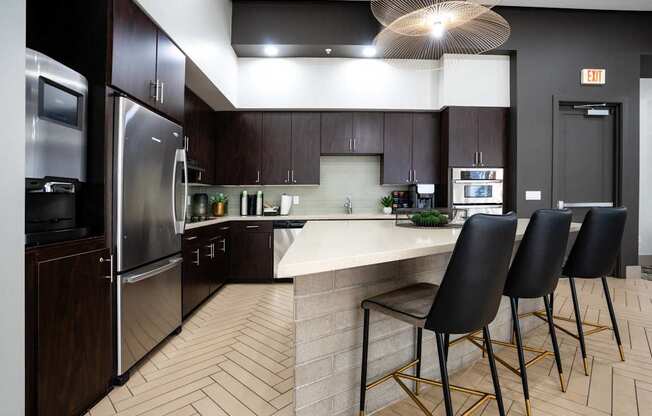 A kitchen with a white counter top and black chairs.