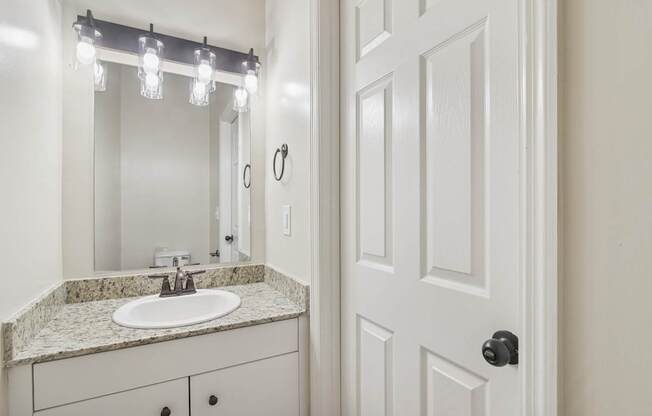 A white bathroom with a sink and mirror.