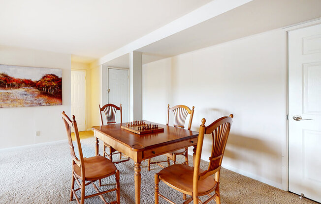 A wooden table with chairs in a room with a painting on the wall.