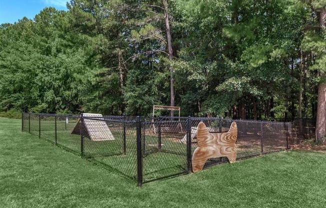 A dog house is behind a chain link fence in a grassy area.