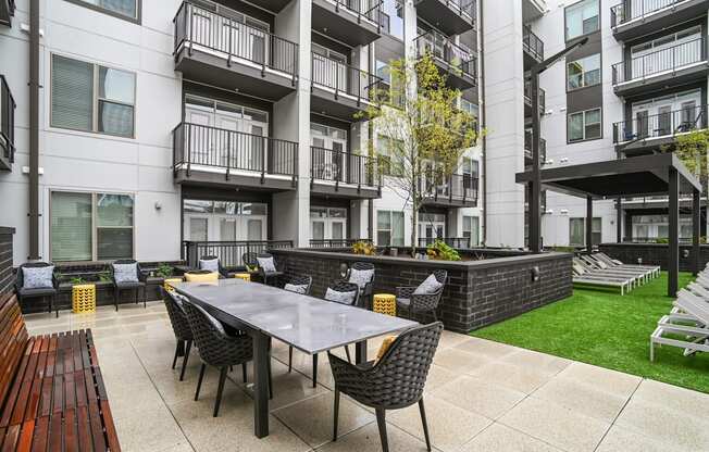 an outdoor patio with a table and chairs in front of an apartment building at Link Apartments® Mint Street, Charlotte, NC, 28203