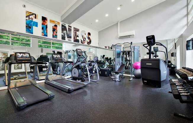 A gym with a variety of equipment including treadmills, exercise bikes, and weights.