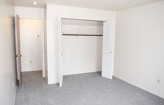 an empty bedroom with a closet and an open door at Seville Apartments in Kalamazoo, MI 49009