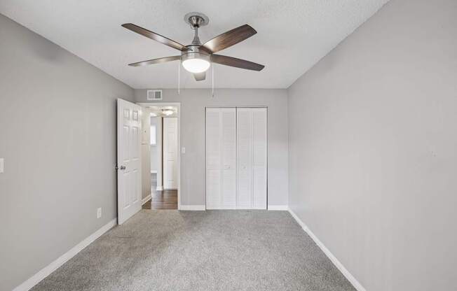 A room with a ceiling fan and carpeted floor.