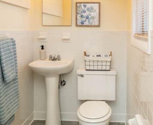 A bathroom with a toilet, sink, and mirror.