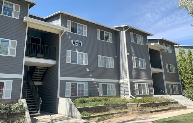 an apartment building with grey siding and a blue sky in the background