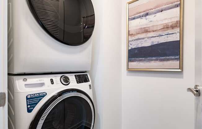 a washer and dryer in a laundry room with a painting on the wall