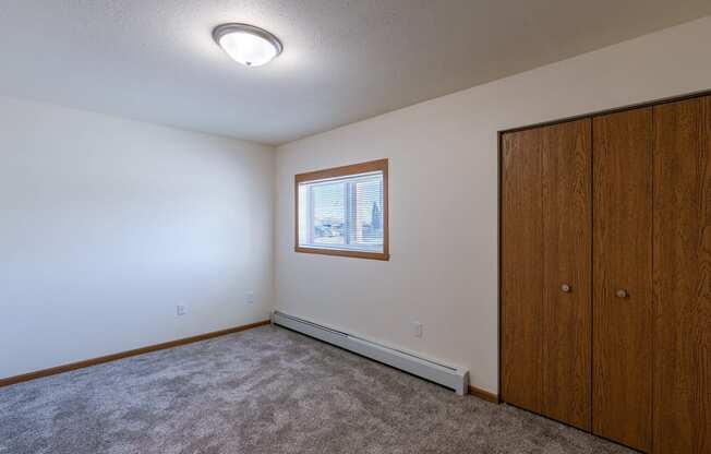 a bedroom with a closet and a window. Fargo, ND Westwood Apartments