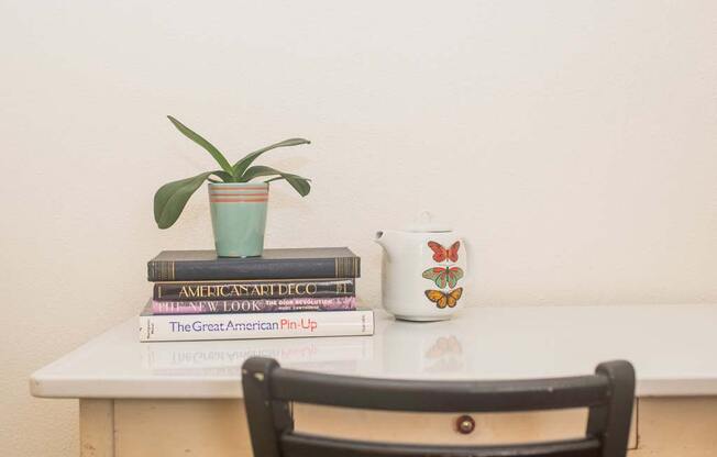 a table with a chair and a plant on top of a stack of books at MILEPOST 5 Apartments, Oregon, 97213