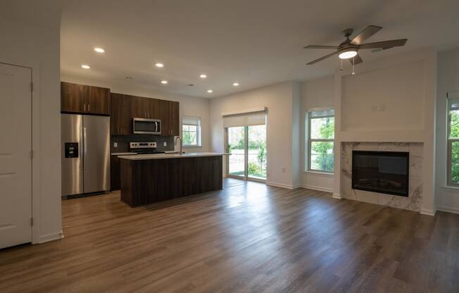 an empty living room with a fireplace and a kitchen at The Clearing at ONE28, Olathe, KS, 66062