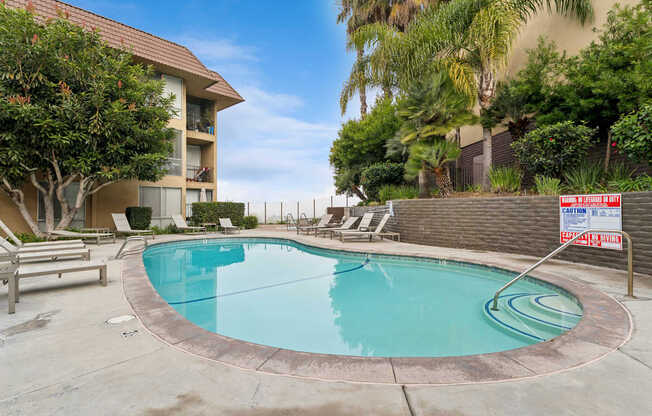 A pool surrounded by a concrete patio and a fence.