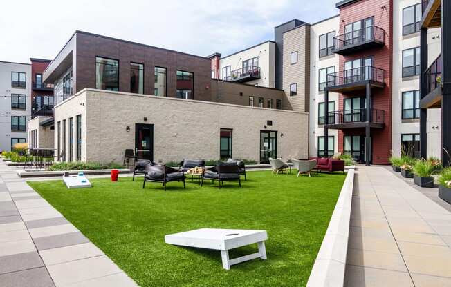 Large green space outlined by sidewalks with plenty of outdoor game options like cornhole.