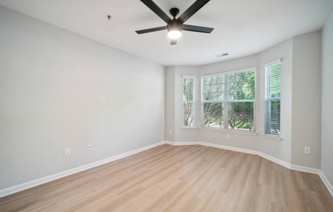 an empty living room with a ceiling fan and a window
