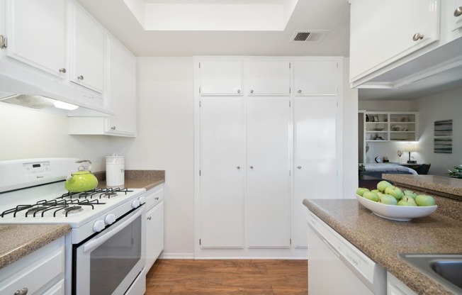 a kitchen with white cabinetry and a white stove top oven