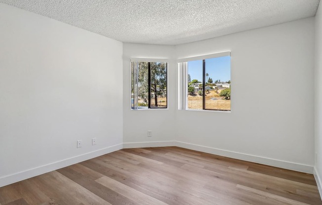 A room with two windows and wooden flooring.