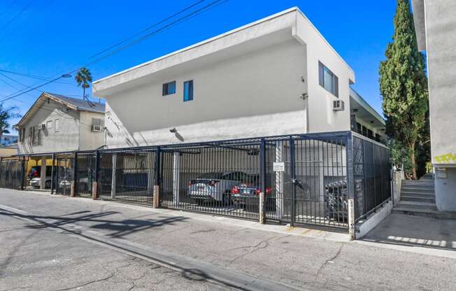 a white building with a gate and cars parked in front of it