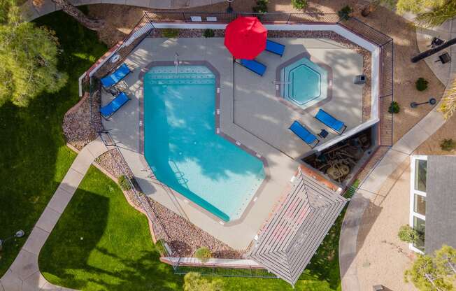 arial view of a swimming pool with a red umbrella in the middle