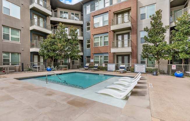 A large swimming pool in the middle of a courtyard surrounded by apartment buildings.