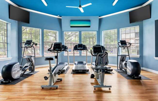 a gym with cardio equipment and windows at Villages of Cypress Creek, Houston, TX