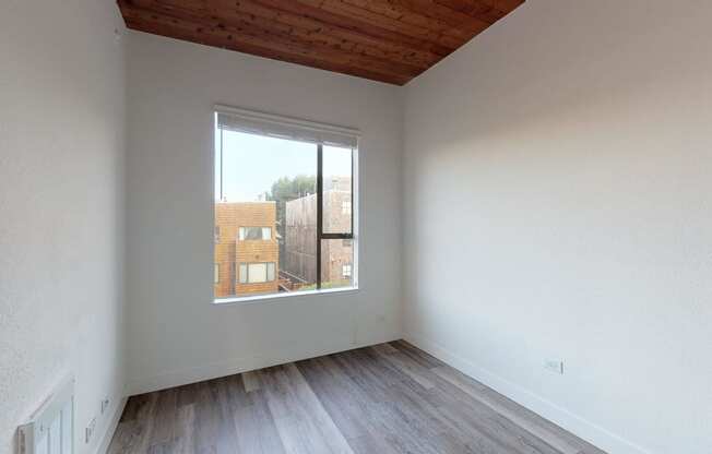 a bedroom with a large window and hardwood floors