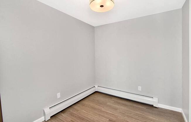 an empty room with white walls and wood floors at Springwood Gardens, New Britain, Connecticut