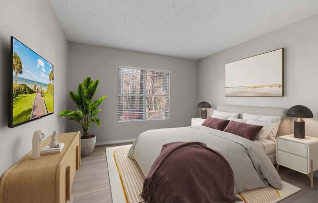 A modern bedroom with a large bed, a TV on the wall, and a potted plant.