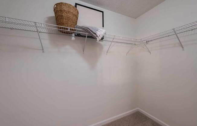 A room with a white wall and a shelf with a basket on it.