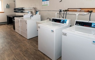 a row of washers and dryers sit in a room