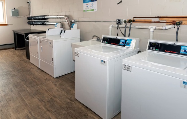 a row of washers and dryers sit in a room