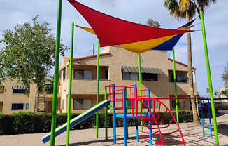 A playground with a red, yellow, blue and green slide.