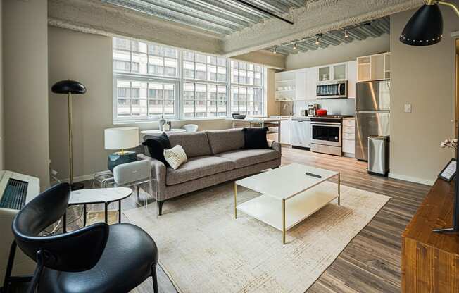 a living room with a couch and a coffee table    and a kitchen
