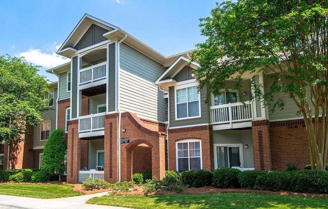 Meticulously maintained grounds with mature trees surround the soft green paint and brick exterior apartment homes at Autumn Park Apartments, Charlotte, NC 28262