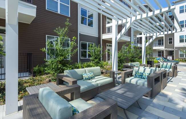 a patio with tables and chairs under a white pergola