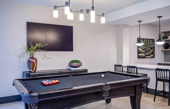 A pool table in a room with a TV on the wall.