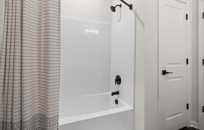 A white bathroom with a shower curtain and a white door.