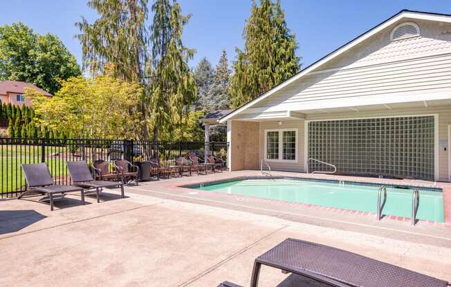 a swimming pool in front of a house with patio furniture