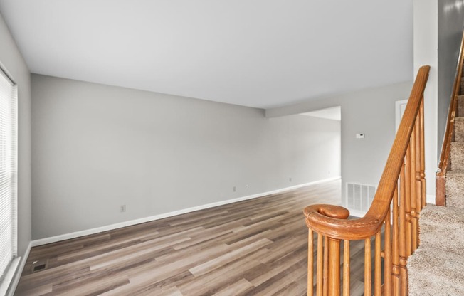 A room with wooden flooring and a staircase with wooden railings.