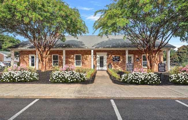 the front of a brick building with trees and flowers