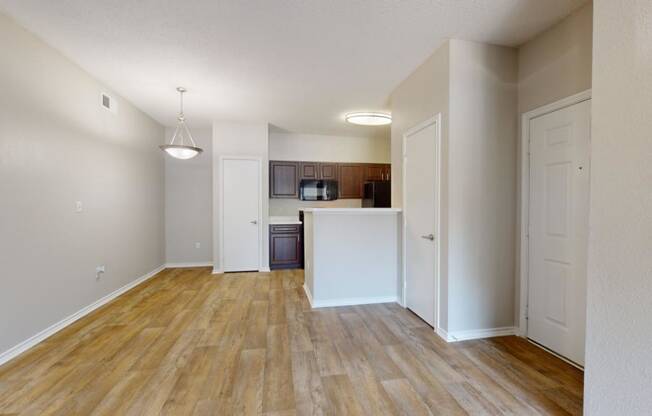 an empty living room and kitchen with wood flooring
