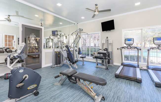 a gym with cardio equipment and a flat screen tv